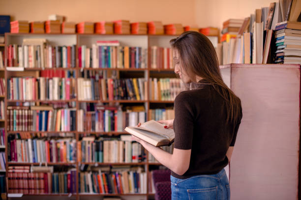 istock Rear view of woman reading in library 949124184