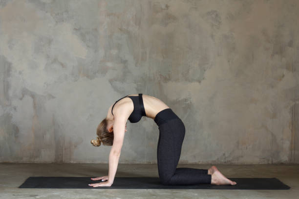 istock Young woman practicing cat pose / Marjariasana against texturized wall / urban background 949126836