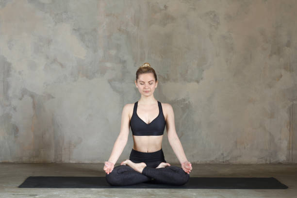 istock Young woman practicing Lotus pose / padmasana against texturized wall / urban background 949126860