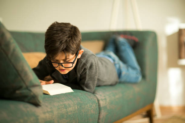 Little boy reading a book in armchair