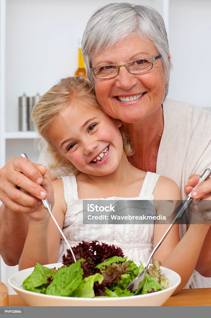 Heureuse grand-mère et petite-fille mangeant une salade - Photo de Adulte libre de droits