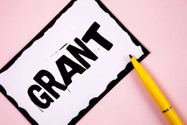 istock Handwriting text Grant. Concept meaning Money given by an organization or government for a purpose Scholarship written on White Sticky note paper on plain Pink background Pen next to it. 949130194