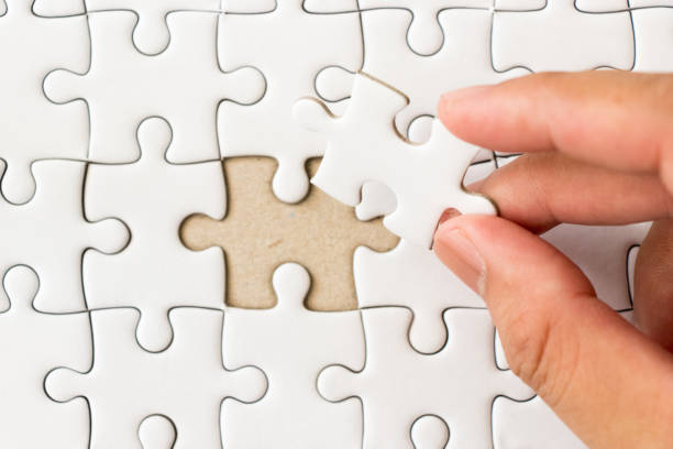 istock Closed up background of white plain jigsaw with hand that hold missing piece to match or fulfill 949130196
