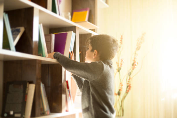 lindo menino escolher um livro na estante - picture book library preschool bookshelf - fotografias e filmes do acervo