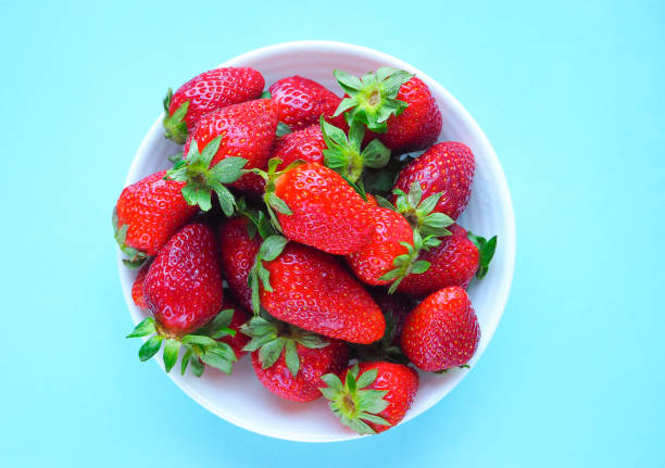 istock Fresh strawberry in white plate on blue background. The view from the top. 949138762