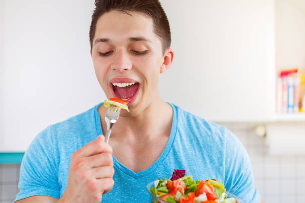 junger mann essen salat in der gesunden küche essen vegan - eating body building muscular build vegetable stock-fotos und bilder
