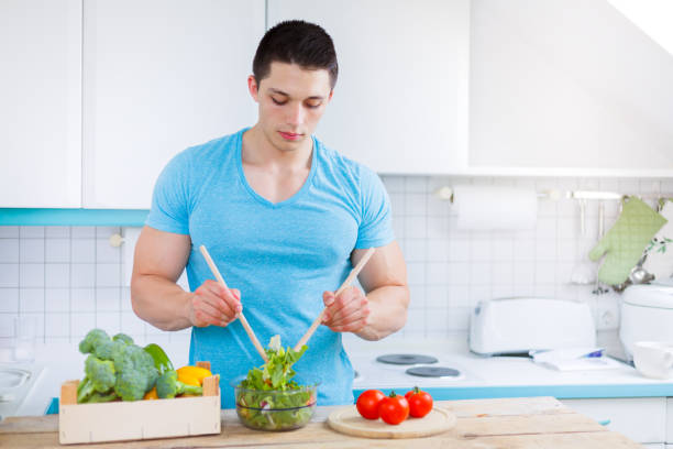 istock Preparing salad food lunch vegetables young man healthy eating copyspace 949140496