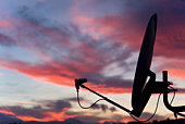 A satellite dish in front of a sunset sky 