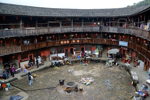 Tourists sightseeing a circular shaped Tulou at Tianluokeng tulou cluster, one of the better known groups of Fujian Tulou. It is located in Nanjing County, Tian Luo Keng Village. The cluster consists of a square earth building surrounded by four round earth buildings figuratively nicknamed 
