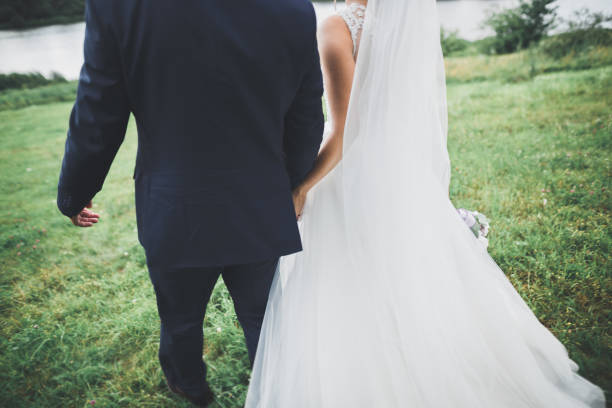 istock Newly married couple running and jumping in park while holding hands 949160290