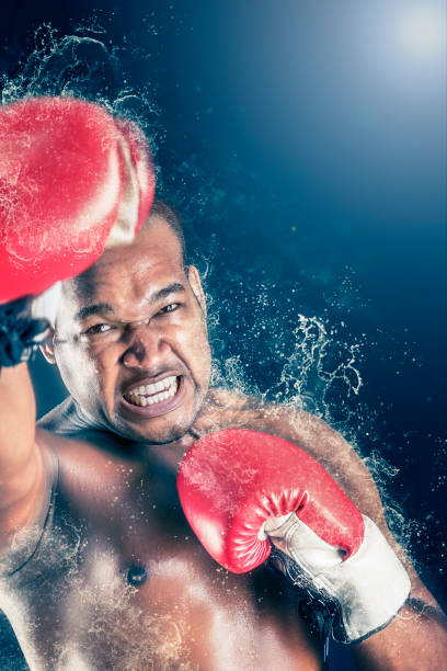 istock Aggressive athlete boxing with gloves at competition in boxing ring 949170696