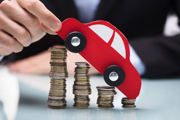 istock Businessman Holding Red Car Over Stacked Coins 949178058
