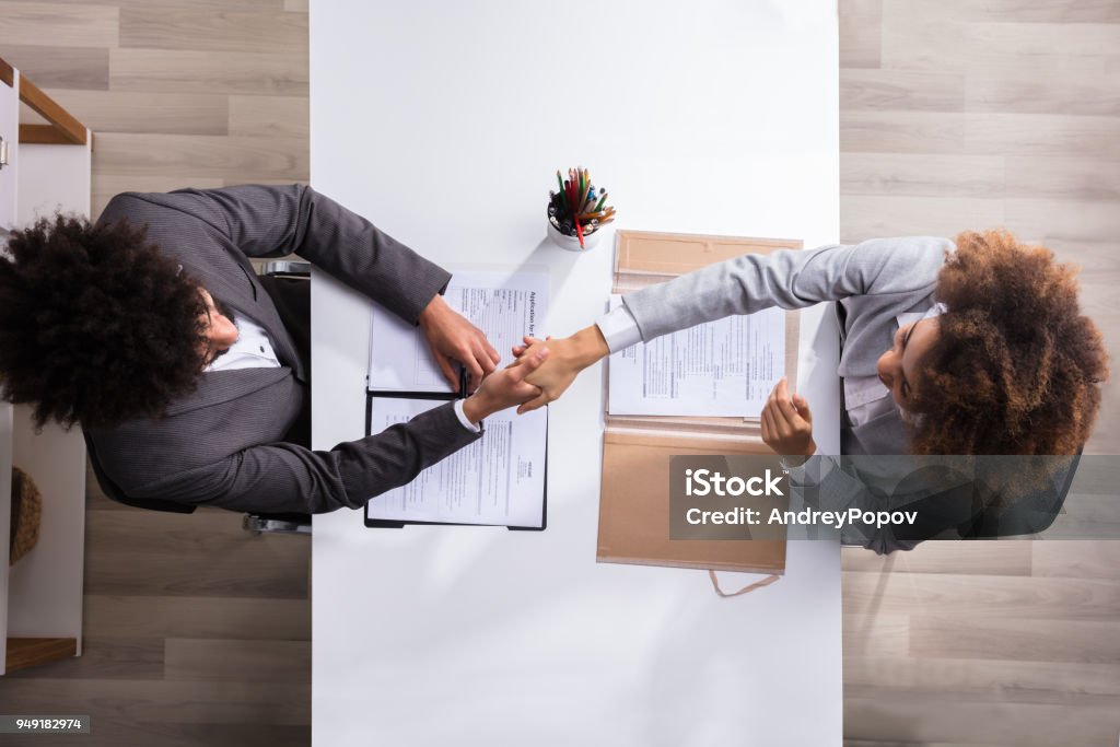 Male Manager Shaking Hands With Female Applicant Elevated View Of A Male Manager Shaking Hands With Female Applicant At Workplace Recruitment Stock Photo