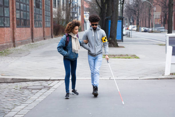 Woman Helping Blind Man While Crossing Road Young Woman Helping Blind Man With White Stick While Crossing Road blindness stock pictures, royalty-free photos & images