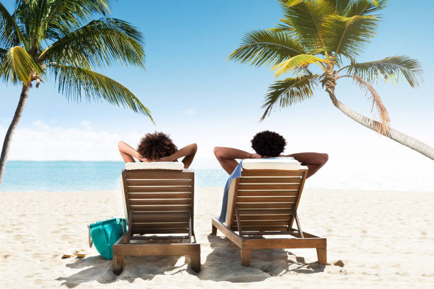 istock Couple relaxing on deck chairs at beach resort 949186112