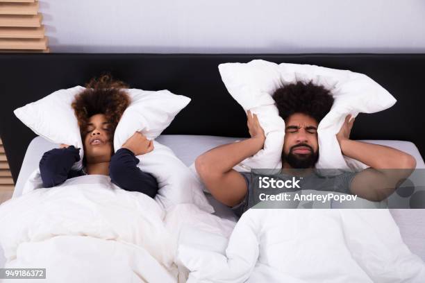 Young Couple Covering Their Ears With Pillow Stock Photo - Download Image Now - Noise, Neighbor, Insomnia