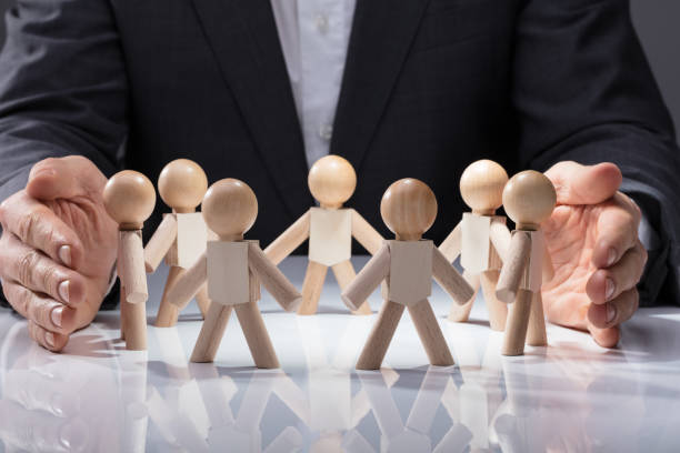 istock Human Hand Protecting Wooden Figures 949186456