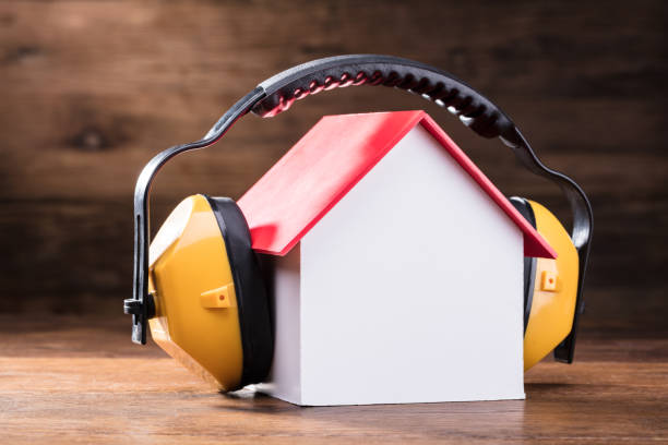 Close-up Of Working Yellow Protective Headphone On The House Model Over The Wooden Table