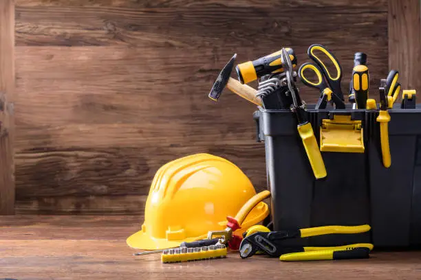 Close-up Of Safety Helmet With Tools In The Black Container On The Wooden Table