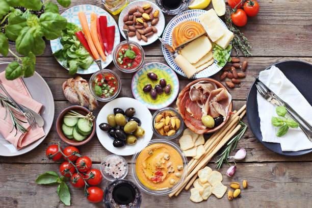 Mediterranean appetizers table concept. Diner table with tapas selection: cured meat and salami, gazpacho soup, jamon, olives, cheese, hummus and vegetables.