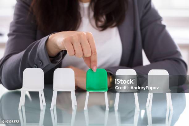 Businesswoman Choosing Green Chair Among White Chairs In A Row Stock Photo - Download Image Now