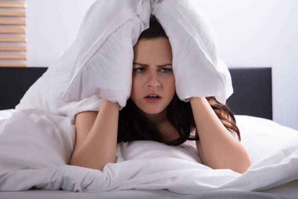 istock Woman On Bed Covering Her Ear With Bedsheet 949196334