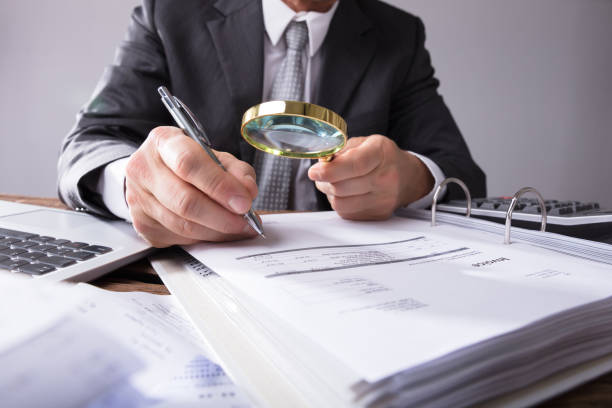 istock Businessperson Looking At Receipts Through Magnifying Glass 949198982