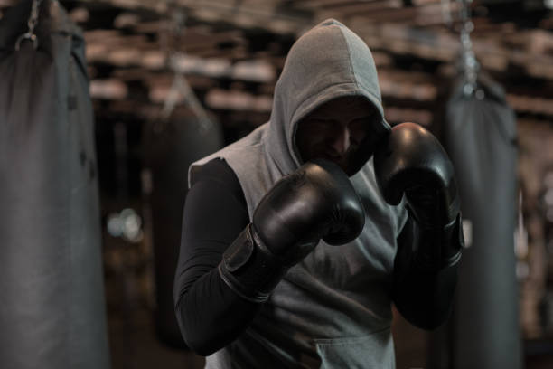Middle Aged Redhead Handsome Boxer Fighter training with Heavy bag in Gym Setting