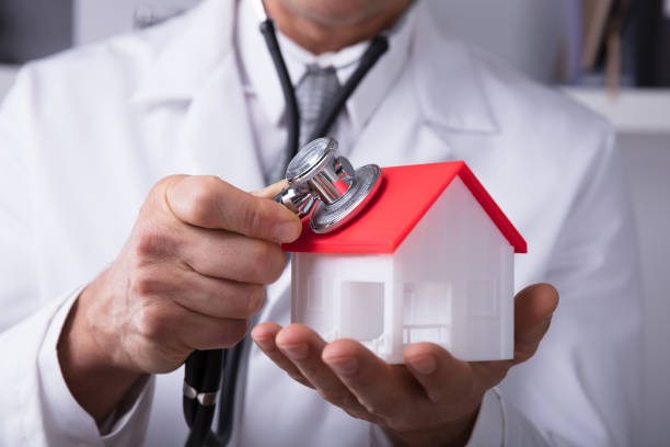 istock Doctor Holding Stethoscope On House Model 949202848