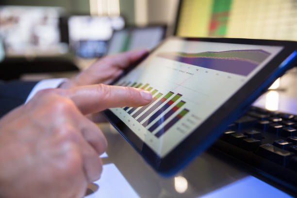 Close-up Of A Businessperson's Hand Looking At Financial Graph On Digital Tablet In Office