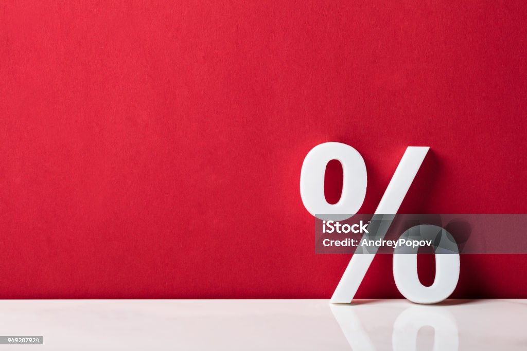 Close-up Of A Percentage Sign Close-up Of A Percentage Sign Leaning On Red Wall Sale Stock Photo