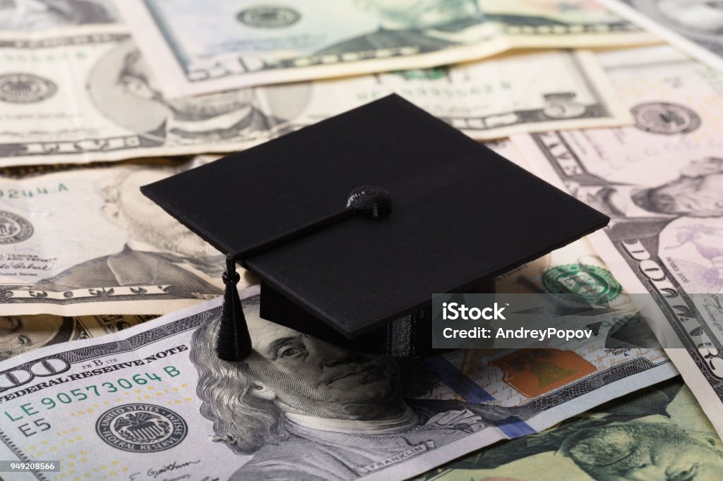 Graduation Cap On Dollar Banknotes Close-up Of Black Graduation Cap On Dollar Banknotes Studying Stock Photo