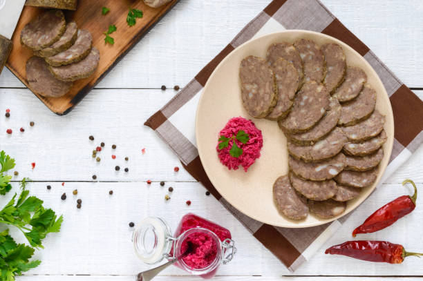 fait maison diététique saucisse de foie sur une table en bois blanc. saucisses coupées en morceaux sur une assiette avec la sauce au raifort. vue de dessus. - horseradish homemade eating food and drink photos et images de collection