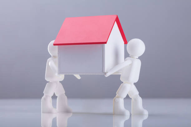 istock Close-up Two Human Figures Carrying House Model 949211084