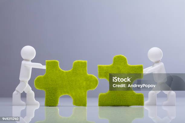 緑のジグソー パズルを解く 2 つのミニチュア人物像 - 合併買収のストックフォトや画像を多数ご用意 - 合併買収, ビジネス, チームワーク