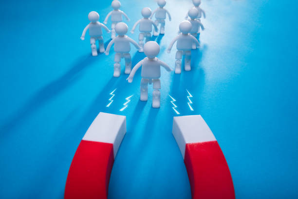 Elevated View Of Horseshoe Magnet Attracting Human Figures Isolated On Blue Background
