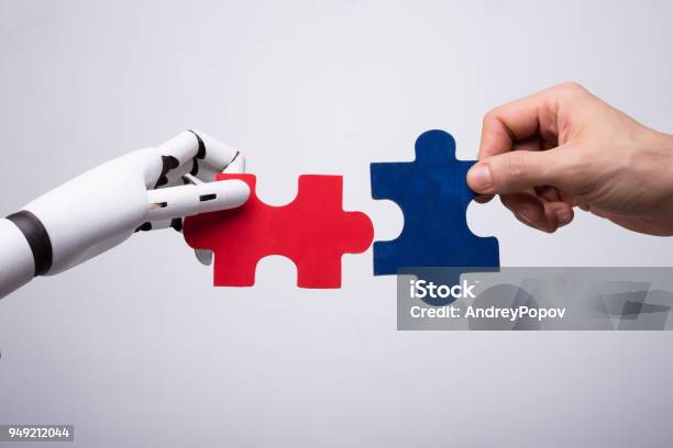 Robot And Human Hand Holding Jigsaw Puzzle Stock Photo - Download Image Now - Artificial Intelligence, People, Robot