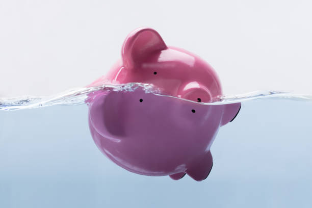 piggy bank drowning in water - debt finance despair water imagens e fotografias de stock