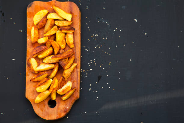 istock Fried potatoes on wooden board. Dark background. Top view. 949212338