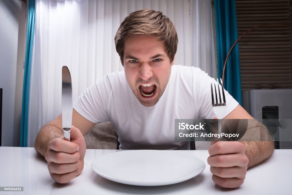 Angry Man Holding Knife And Fork Angry Man Holding Knife And Fork With Empty Plate On Table Hungry Stock Photo