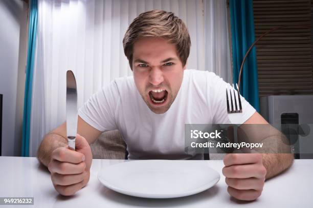 Angry Man Holding Knife And Fork Stock Photo - Download Image Now - Hungry, Displeased, Desk