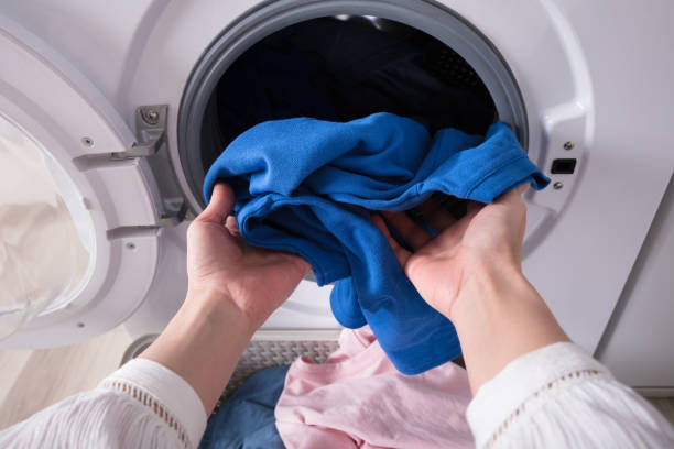 istock Woman's Hand Putting Blue Cloth Into Washing Machine 949218772