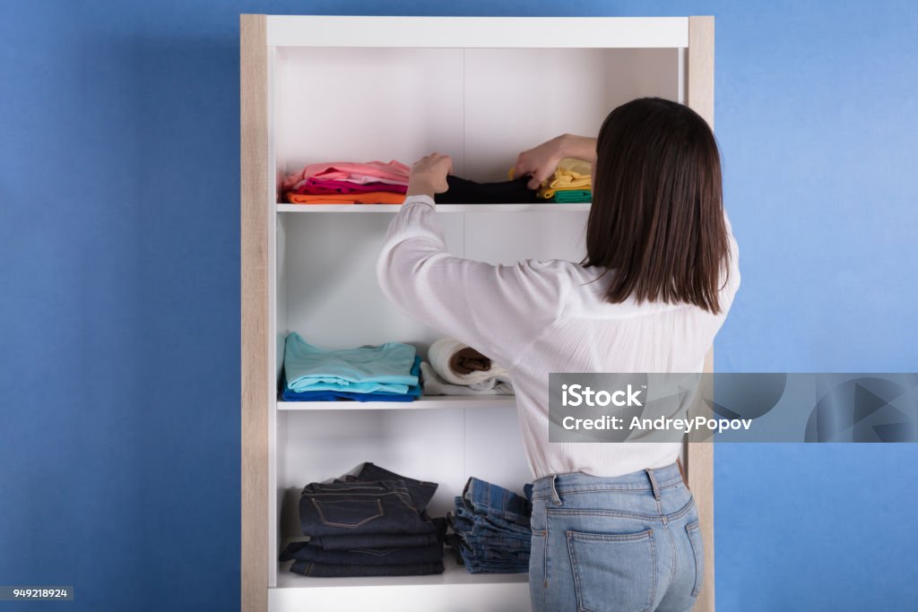 Woman Choosing Cloth From Shelf Rear View Of A Young Woman Choosing Cloth From Shelf Closet Stock Photo