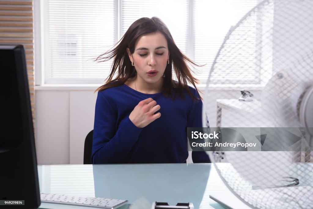 Empresaria disfrutando de la brisa del ventilador eléctrico - Foto de stock de Oficina libre de derechos