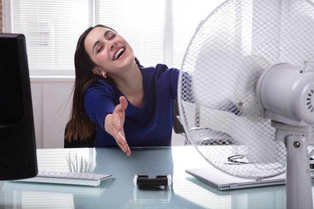 empresária, sentado na cadeira refrigerar-se com ventilador elétrico - office fan - fotografias e filmes do acervo