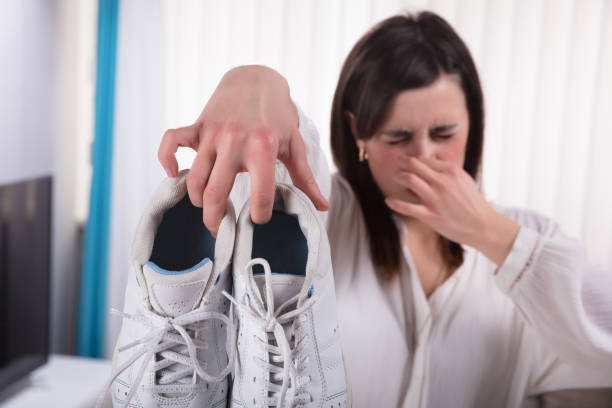 frau mit schmutzigen riechende schuhe - smelling stock-fotos und bilder