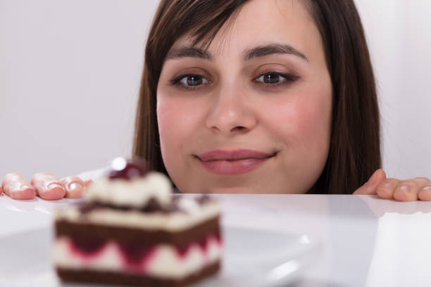 istock Young Woman Looking At Slice Of Cake 949220372