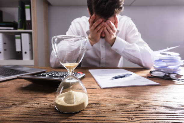 Close-up Of A Hourglass On Wooden Desk Close-up Of A Hourglass In Front Of Upset Businessman In Office time pressure stock pictures, royalty-free photos & images