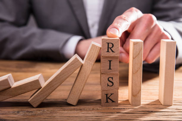 istock Businessperson's Finger Stopping Dominos From Falling 949223076
