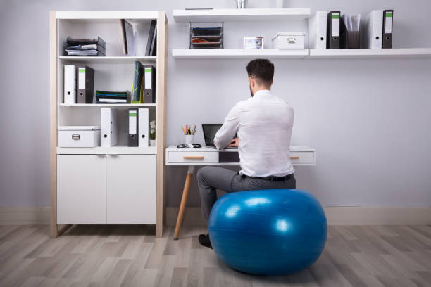 homme d'affaires à l'aide d'un ordinateur portable - yoga ball photos et images de collection